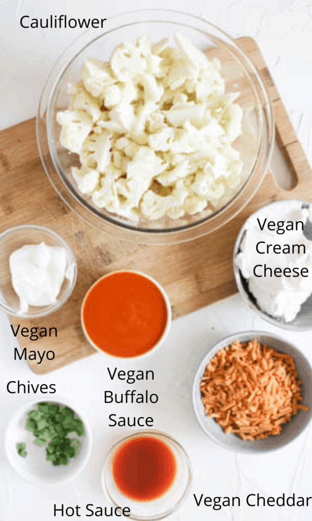 Ingredients for buffalo cauli dip (all ingredients layed out in seperate bowls on top of a cutting board)