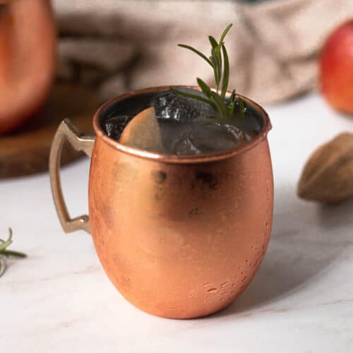 caramel apple mule in a mule mug with rosemary garnish
