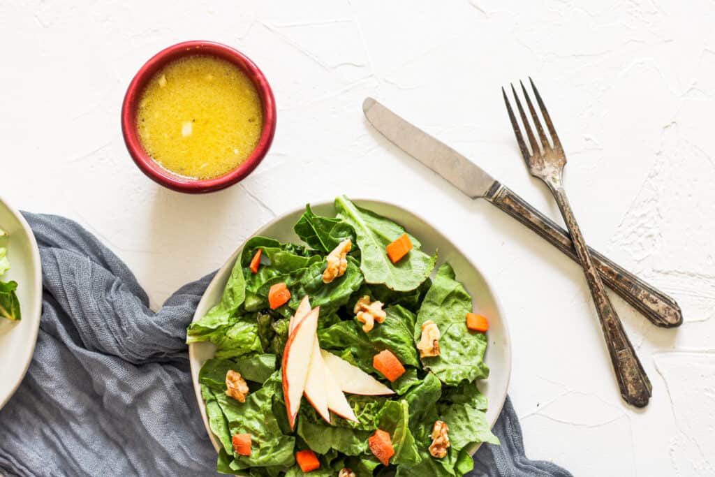 Creamy Apple Cider Dressing in a bowl next to a salad 