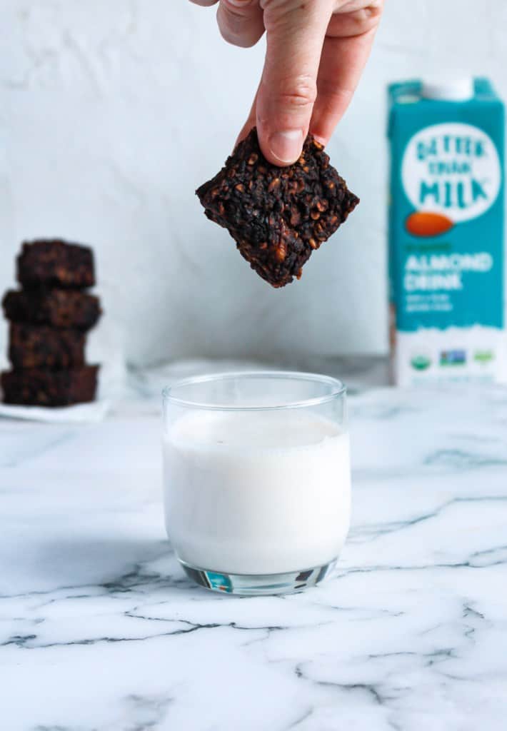 Gooey Vegan Protein Brownies being dunked into a glass of milk