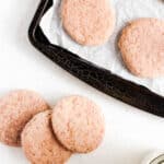Pink Sugar Cookie on a baking tray with parchment paper and some cookies on the white surface