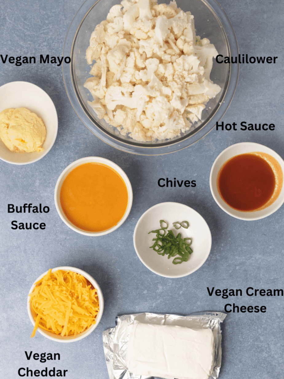 All ingredients for vegan buffalo dip in different bowls with black text labels on a blue surface