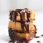 a stack of vegan pumpkin brownies drizzled with melted chocolate