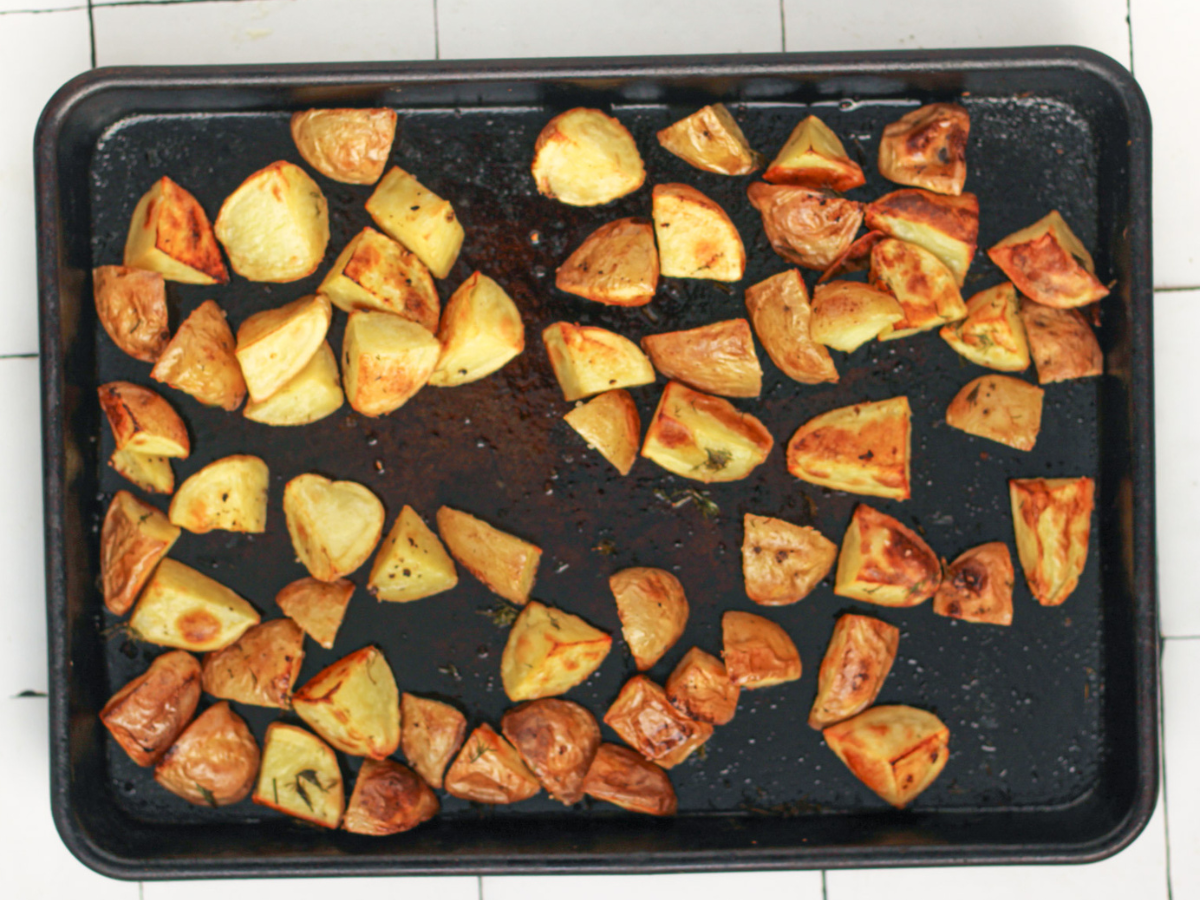 Roasted Potatoes in Ninja Foodi after being roasted with dill, olive oil, salt and pepper on top of them on a baking sheet 