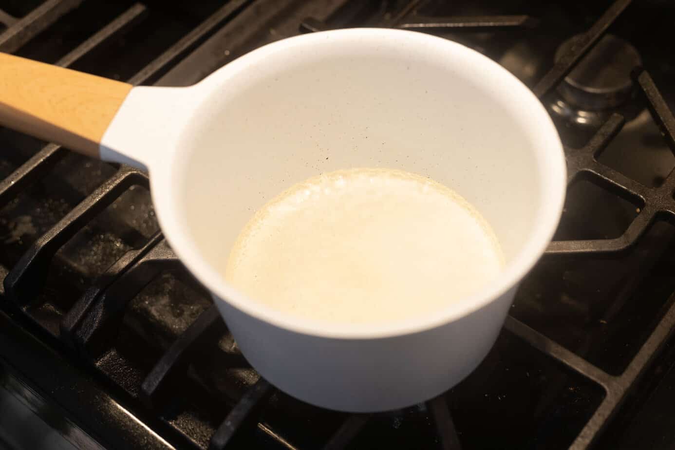 Water boiling in a white sauce pan on a burner
