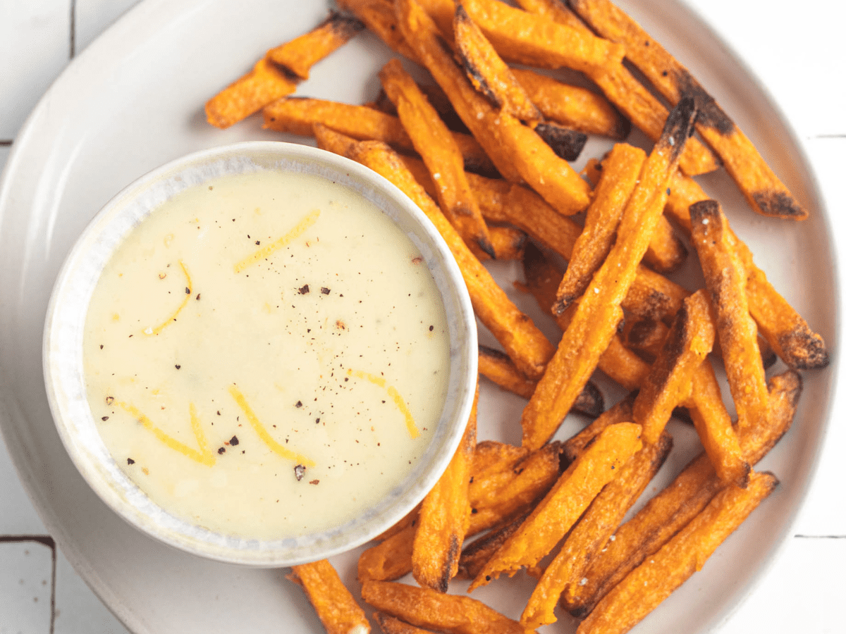 garlic aioli in a bowl with sweet potato fries next to it