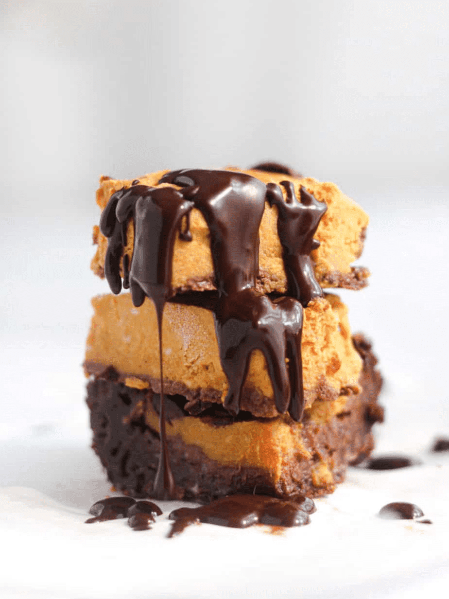 pumpkin brownies stacked on each other with chocolate drizzle on top