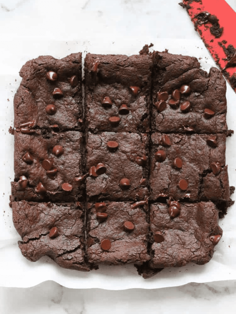 avocado brownies with chocolate chips on top cut into squares on a marble surface 