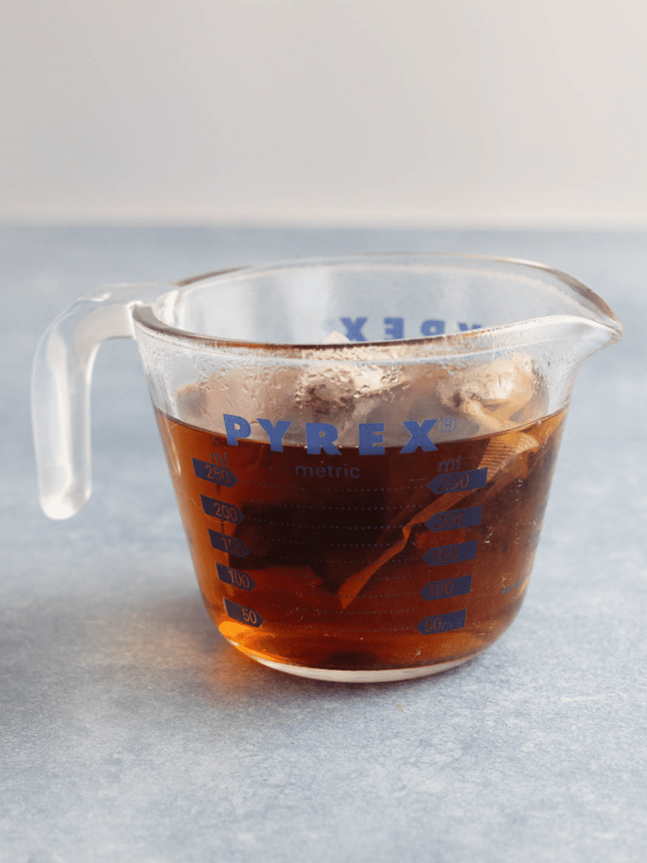 The black tea being brewed in a clear measuring glass cup
