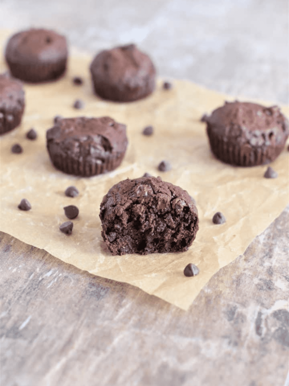 brownie bites with one cut in half on brown parchment paper and chocolate chips around it 
