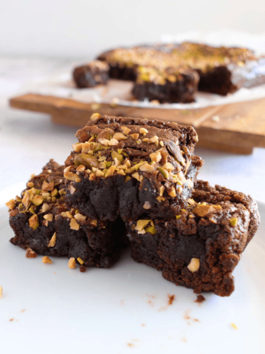 condensed milk brownies cut into three pieces on a plate with nuts on top