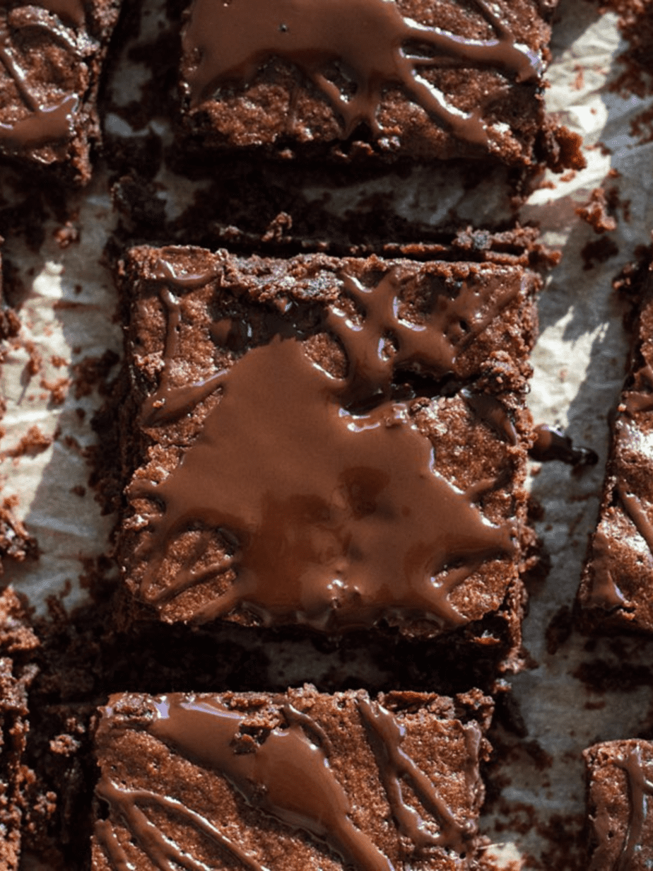 olive oil brownies with a drizzle on top cut into squares on a white surface 