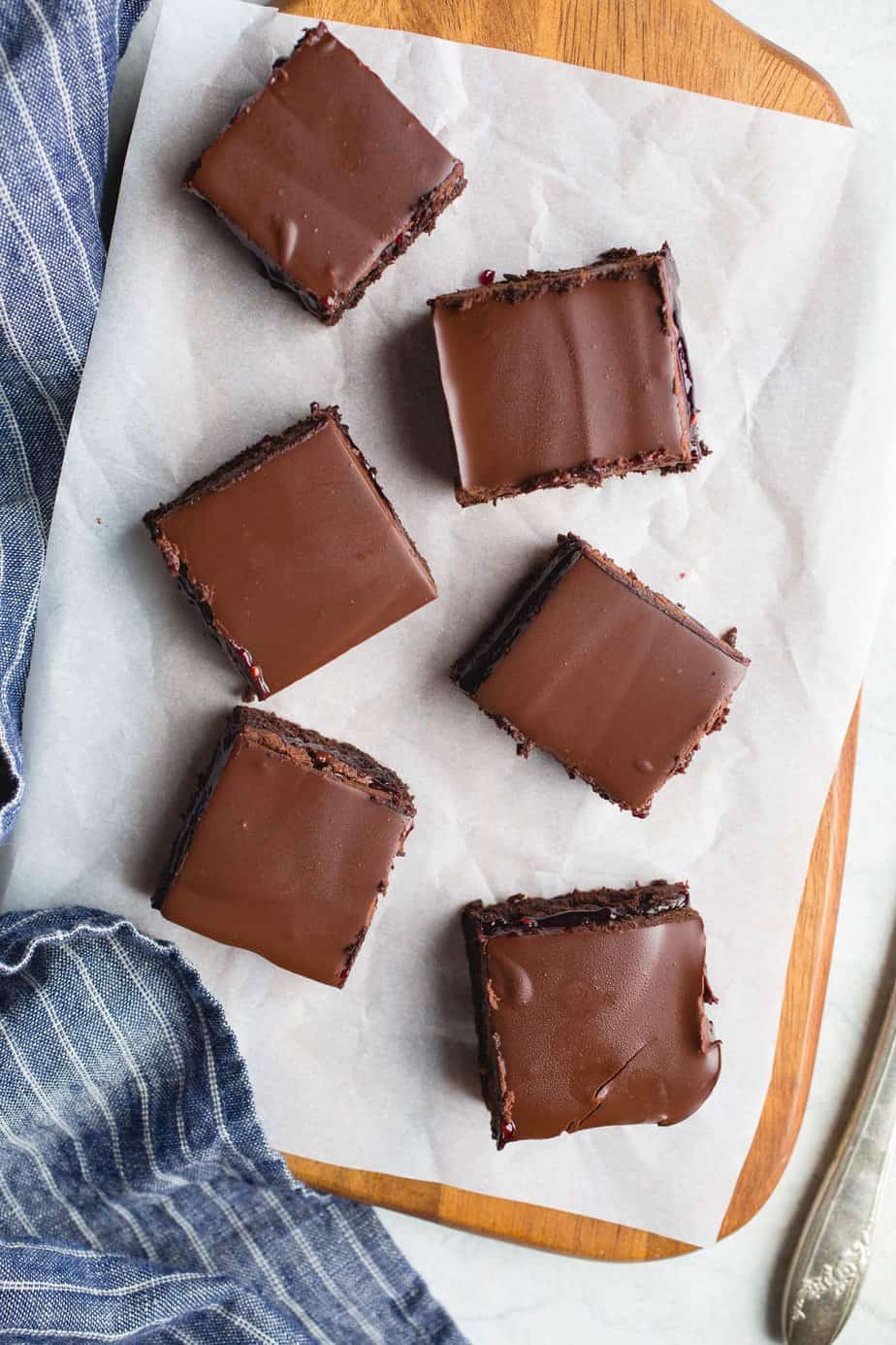 raspberry truffle brownies on top of parchment paper on a cutting board