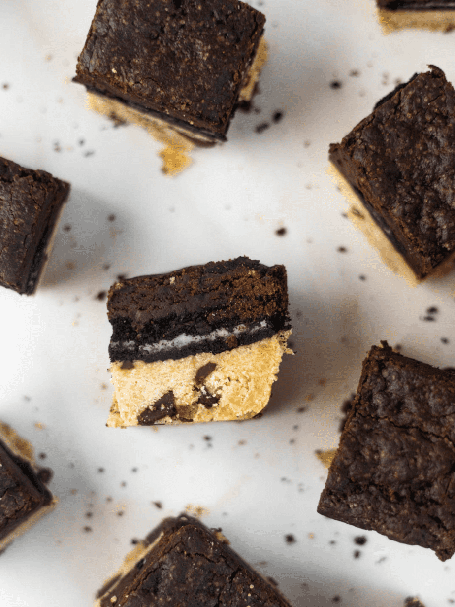 slutty brownie tilted upward to show the layers on a white surface with other brownies around it