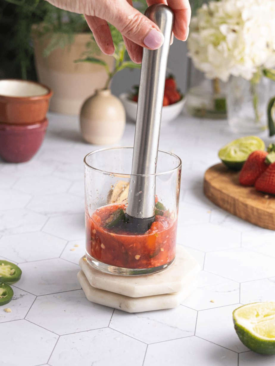 Showing the margarita being made with the fruits in the glass being muddled with a muddler