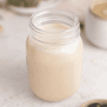 Oat milk coffee creamer in a mason jar fully mixed together with all ingredients in the jar with blueberries next to it