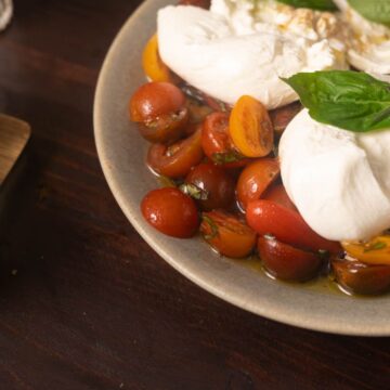 burrata caprese salad on a green plate with basil on top