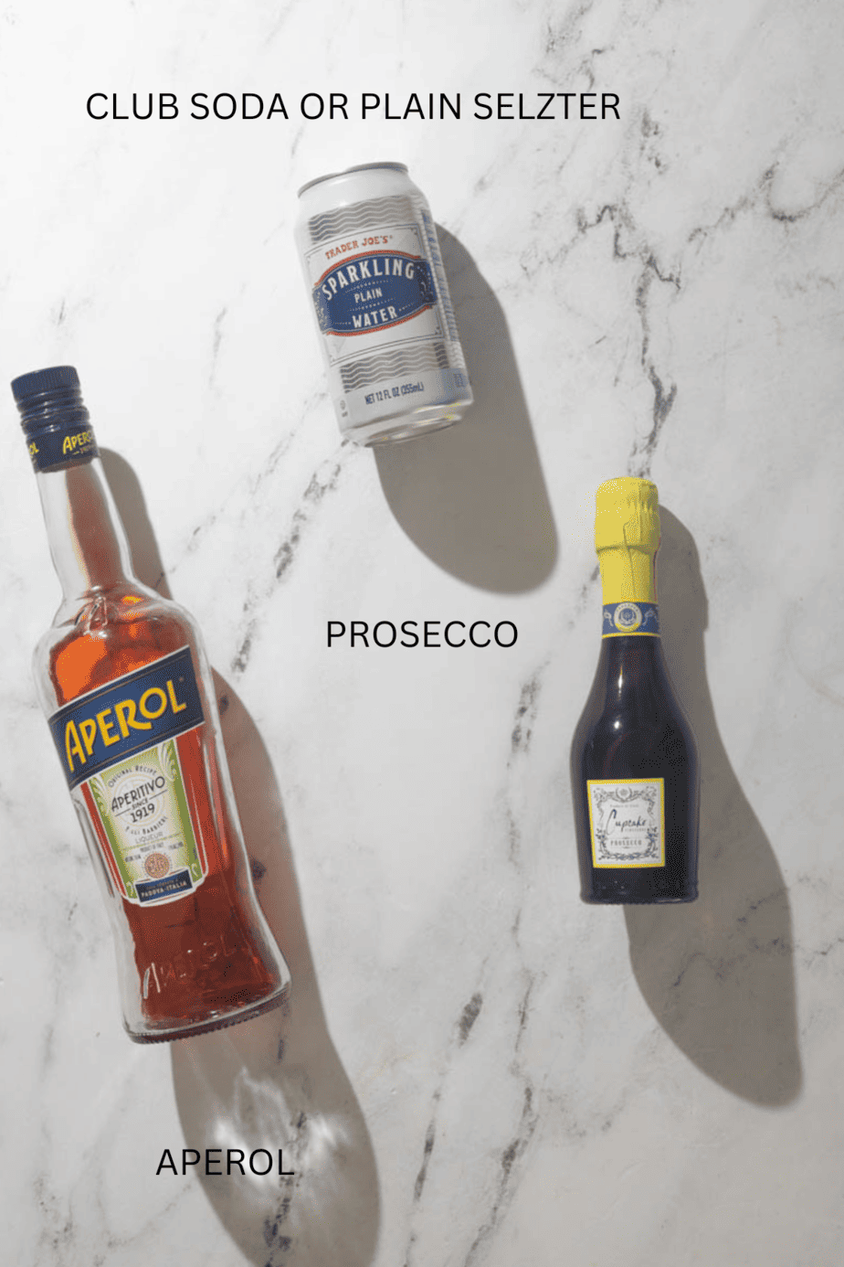 all ingredients to make frozen aperol spritz with text label on marble background