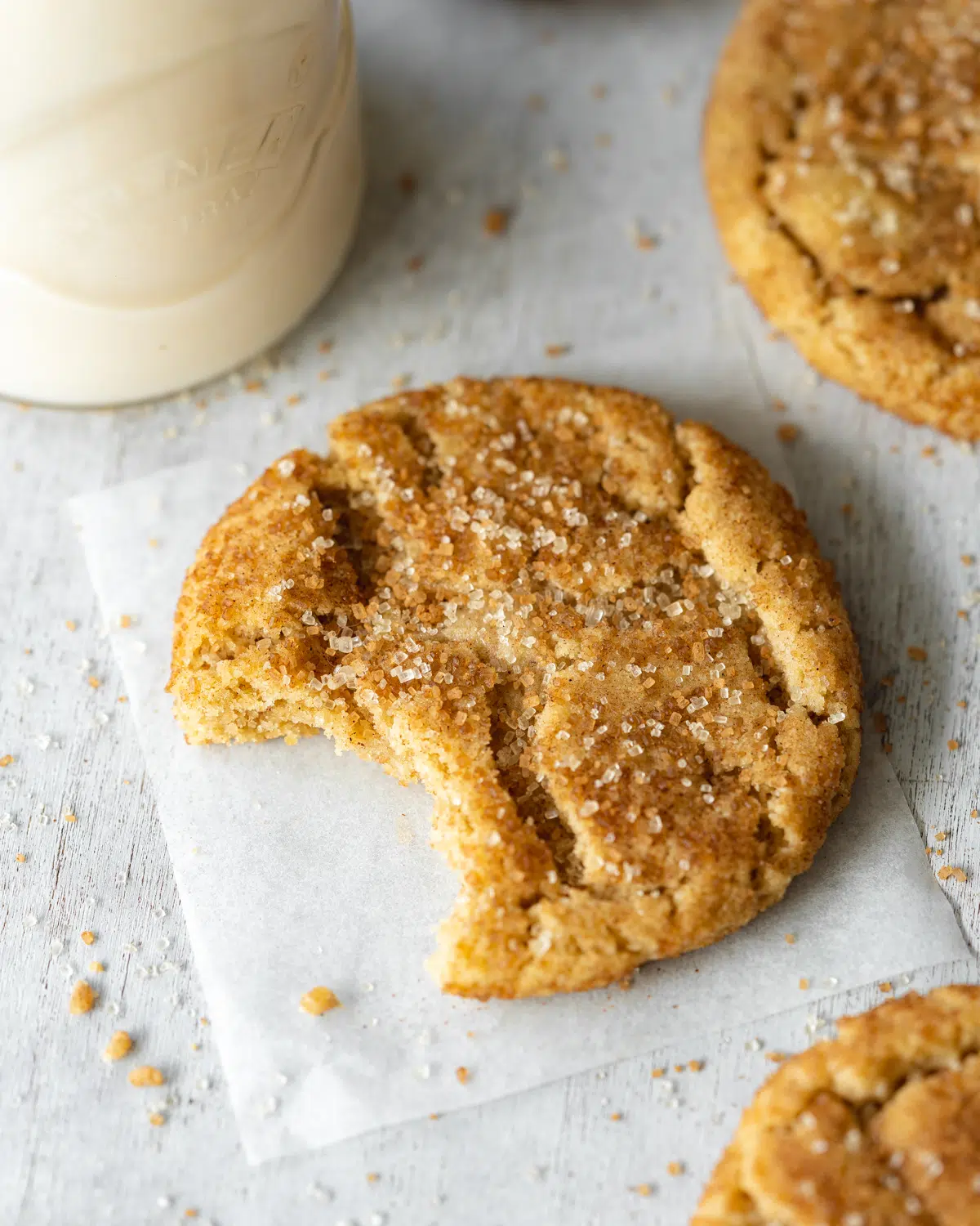 dairy free snickerdoodle cookies on parchment paper with a bite taken out
